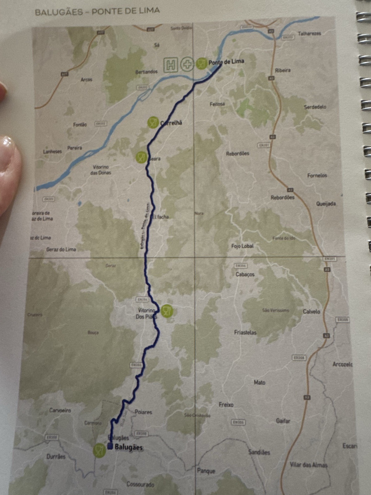 A printed route map headed Balugães to Ponte de Lima, the Camino trail drawn as a
          blue line winding between towns over green hills.