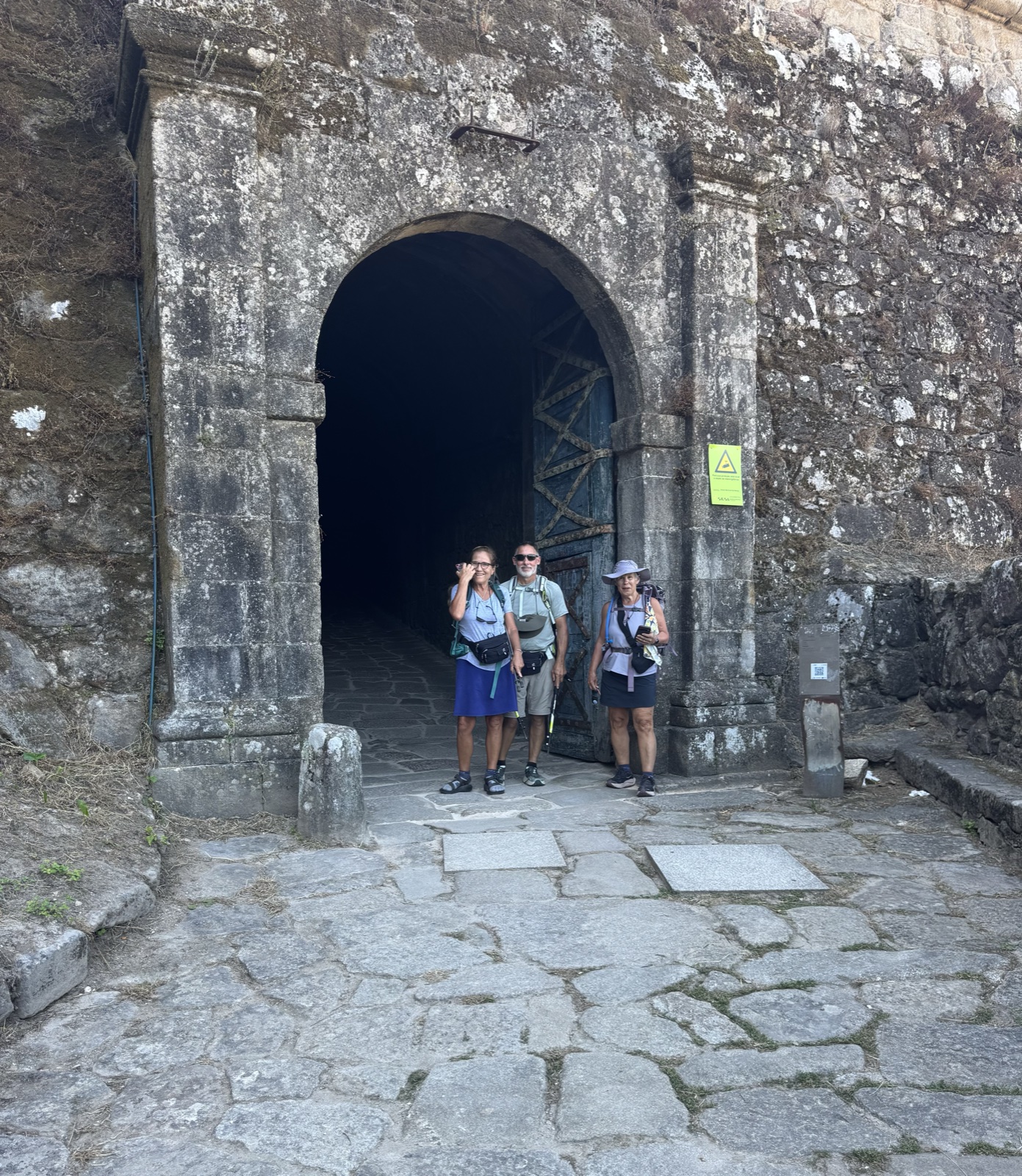 Three pilgrims standing in the dark arched gateway of the old fortress walls.