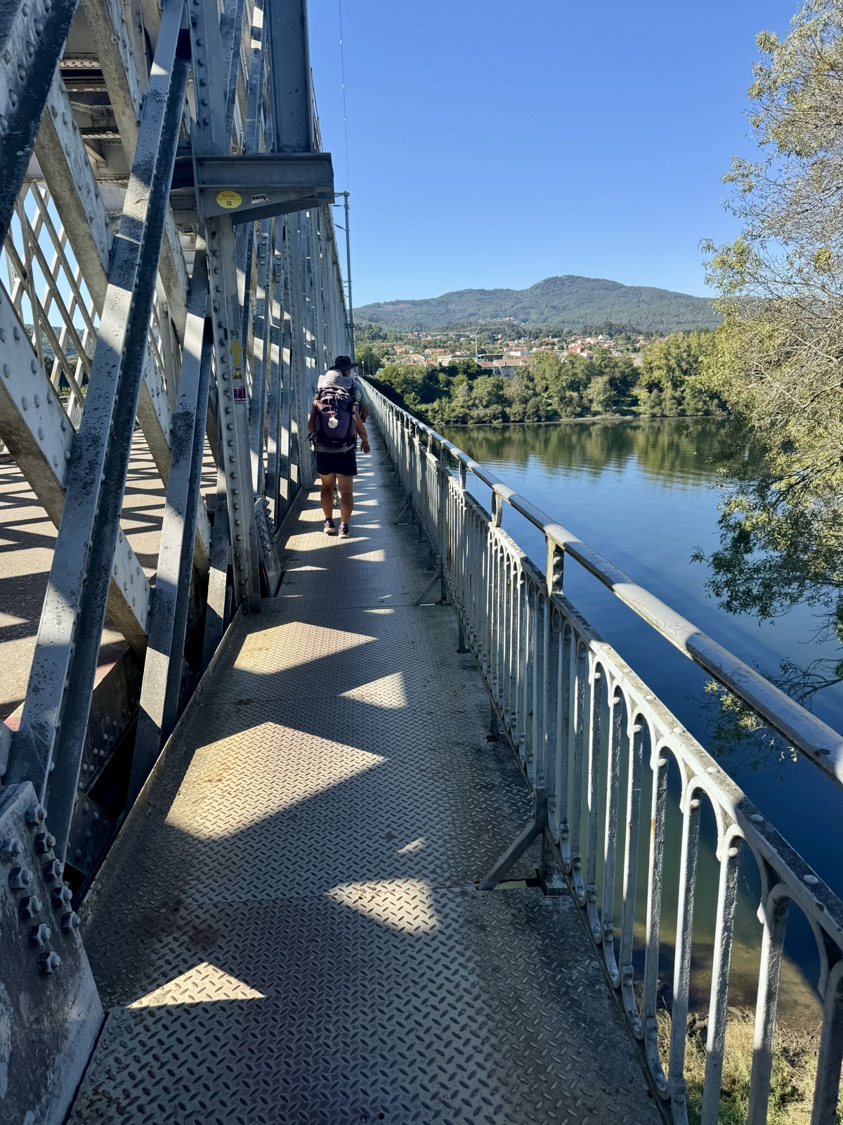The narrow pedestrian walkway of the old iron bridge over the Minho river, a pilgrim far ahead.