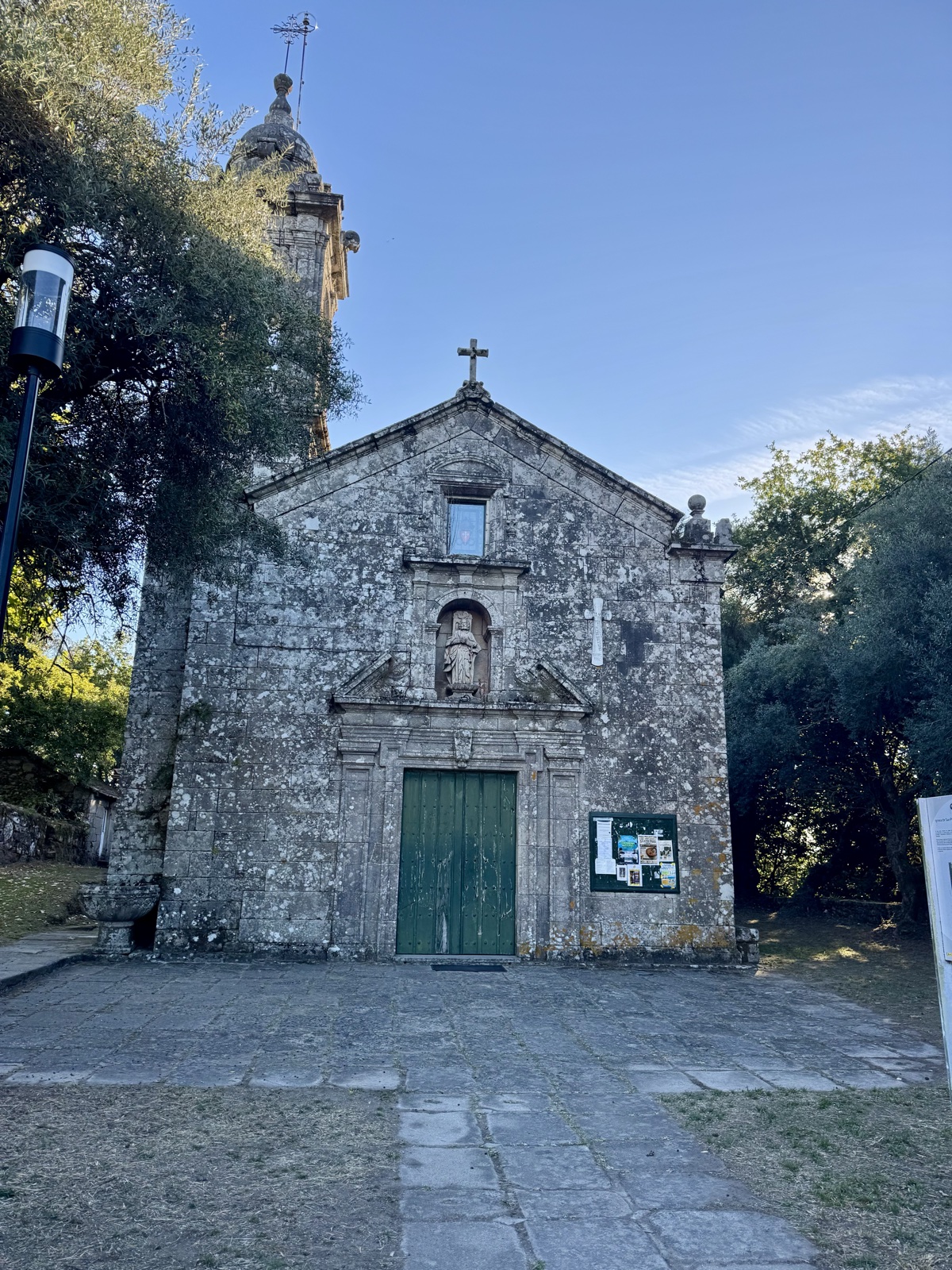 A small granite chapel with a green door and a bell turret, under a clear sky.