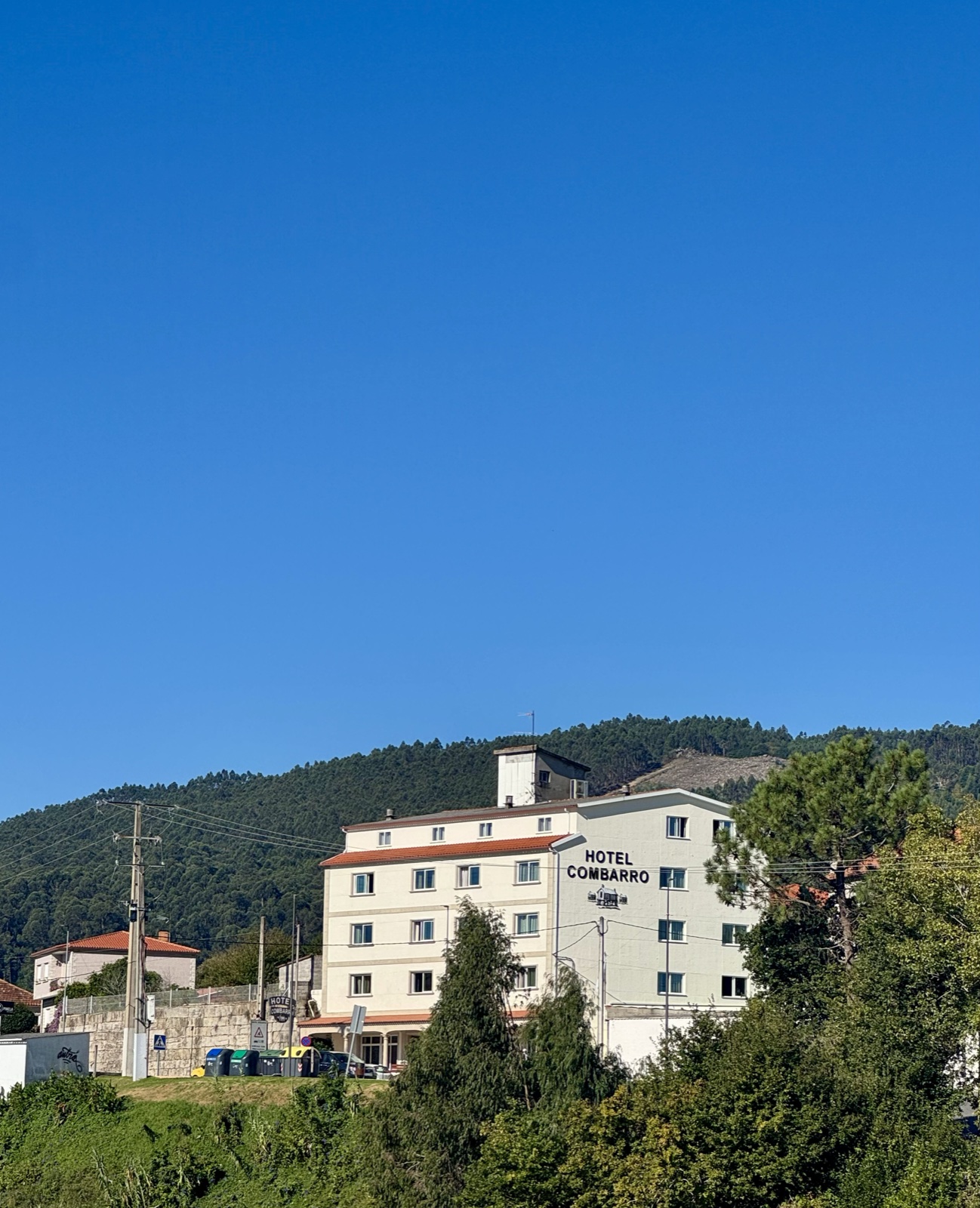A white hotel on a green hillside under a deep blue sky.