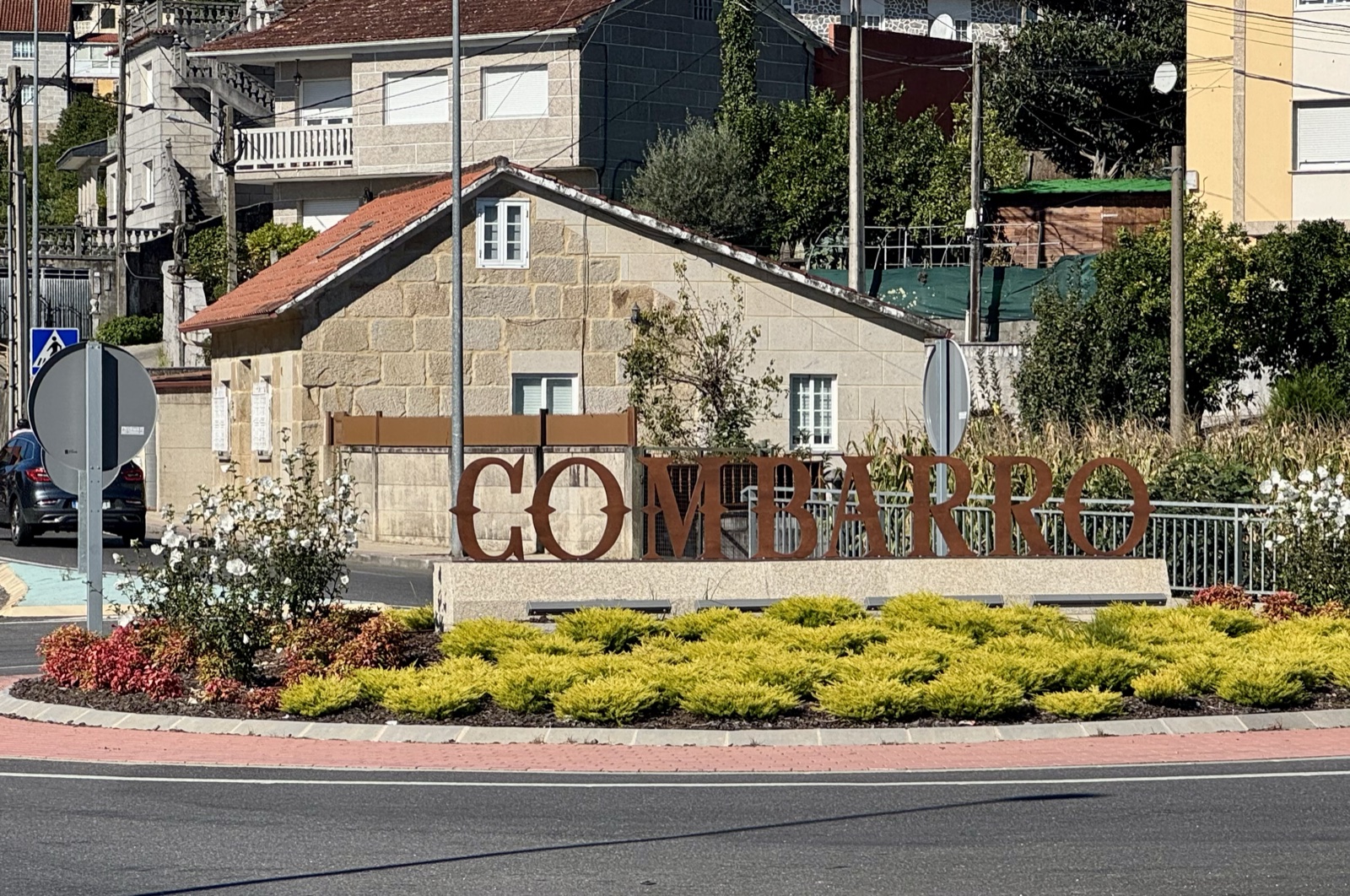 Large rust-coloured letters spelling Combarro in a flower bed at a roundabout.