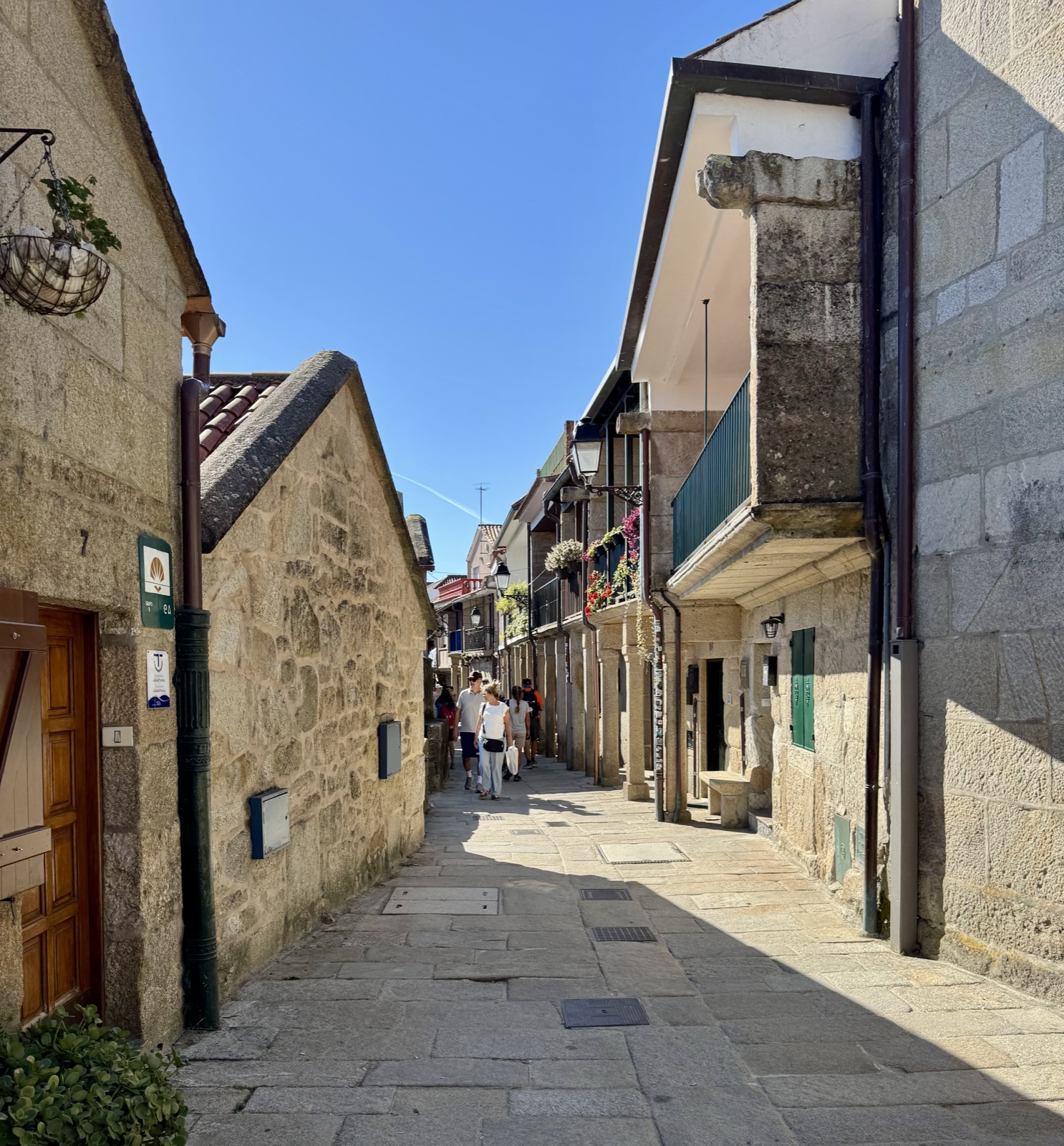 A narrow cobbled street between old granite houses, bright sun on one side.