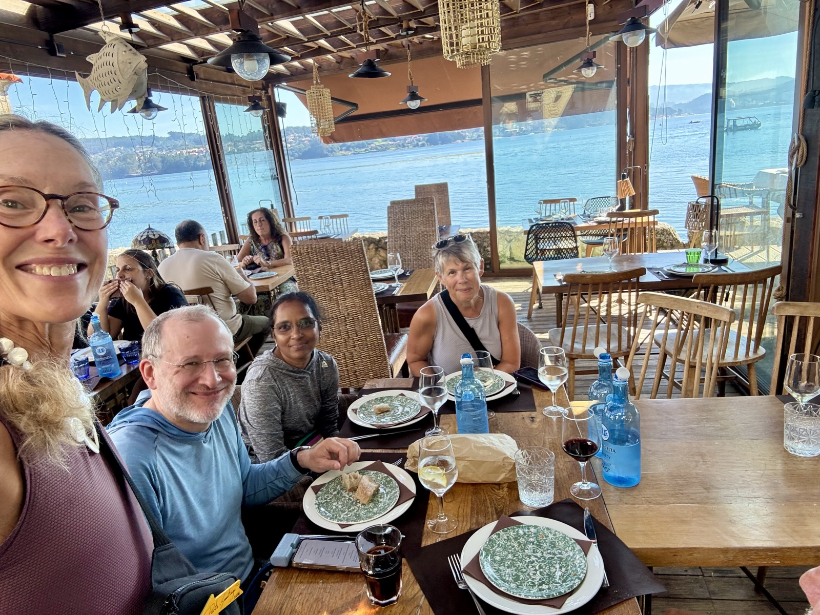 The group around a lunch table in a restaurant with glass walls looking out over the water.