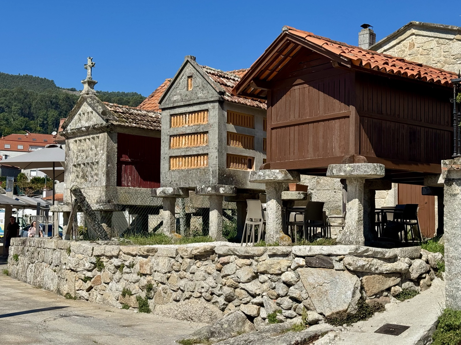 A row of stone and wooden granaries on pillars along a seawall.