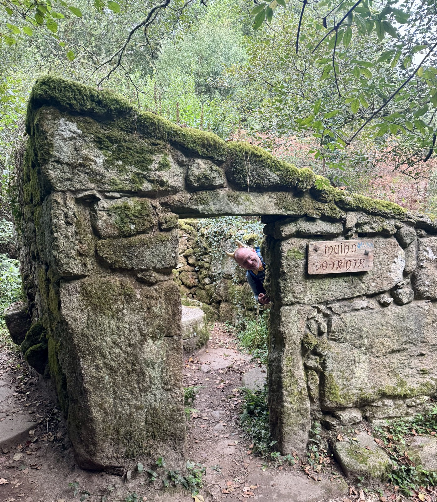 The same stone mill doorway from the side, a hiker peeking out from behind the wall.