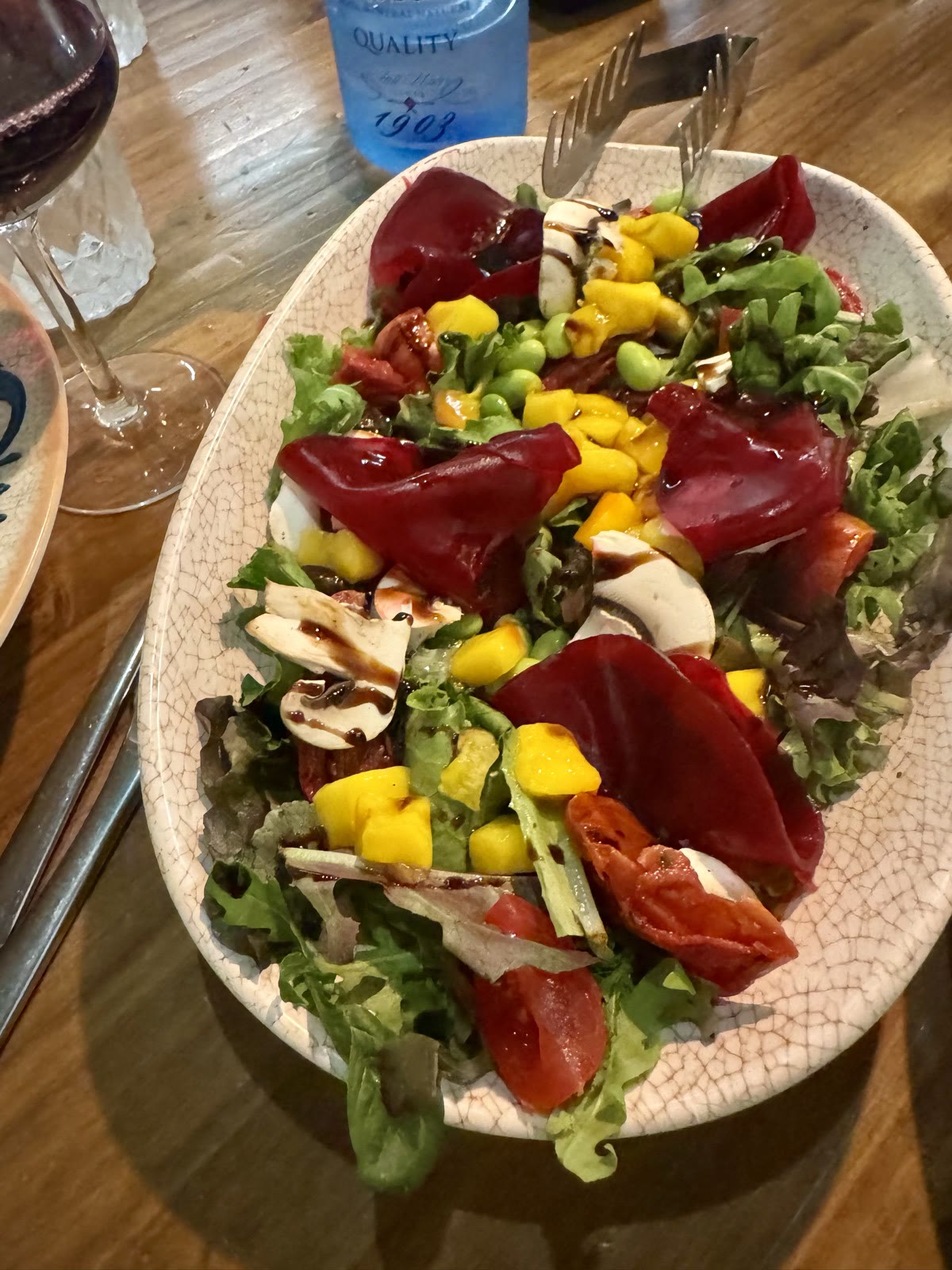 A beet and mango salad with greens, edamame, mushrooms, and balsamic drizzle.
